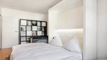 Ein modernes Schlafzimmer mit einem großen Bett, einem Einbauschrank und einem Nachttisch.