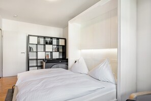 Een moderne slaapkamer met een groot bed, een inbouwkast en een nachtkastje.