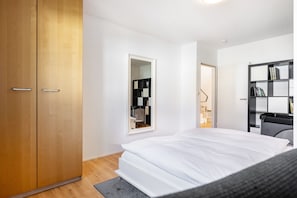 A bedroom with a bed, a wardrobe, a mirror, and a bookshelf.