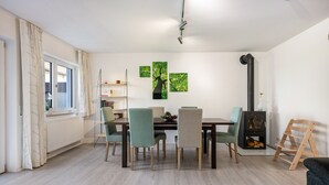 Ein Essbereich mit Tisch, Stühlen, einem Bücherregal und einem Kamin.