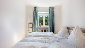 Una camera da letto con un letto, un termosifone e una finestra con tende.