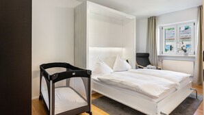 Ein modernes Schlafzimmer mit einem Bett, einem Sessel und einem Babybett.