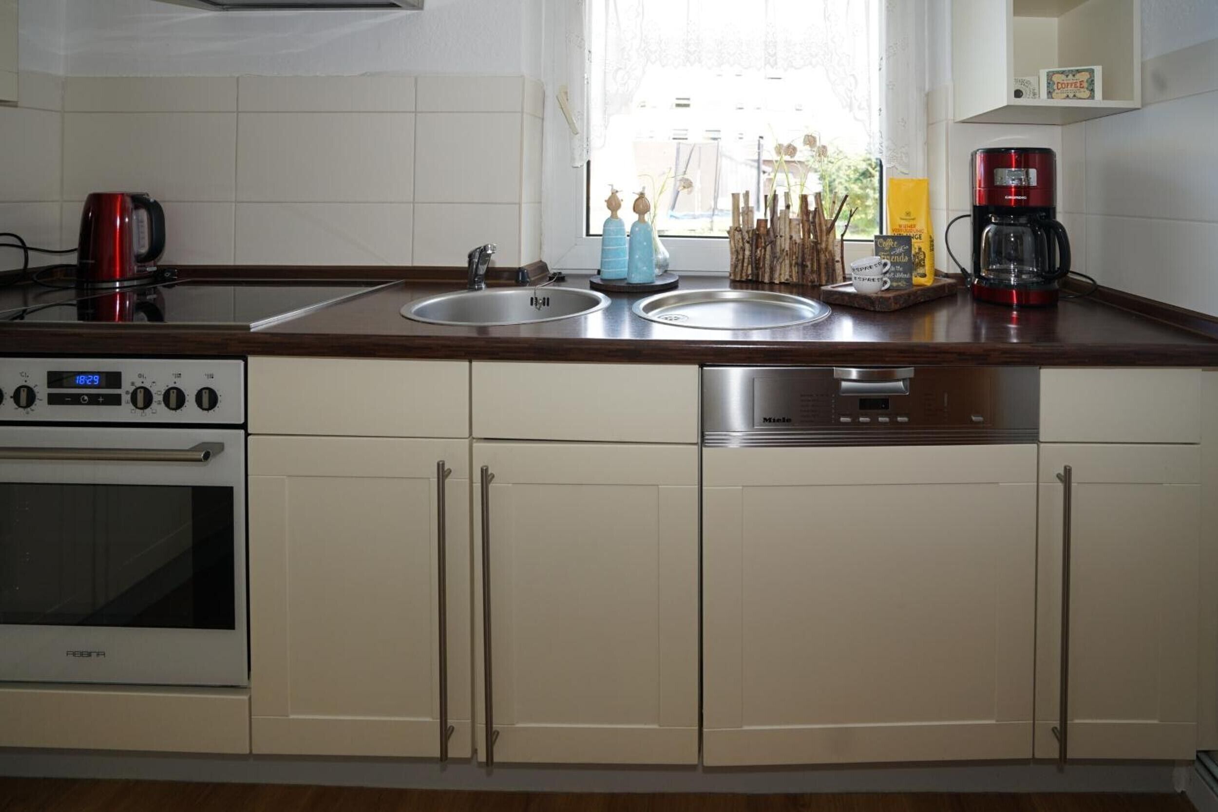 A kitchen with a stove, oven, sink, and coffee maker.