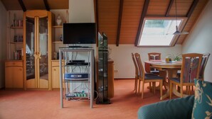 A room with a wooden ceiling, a television on a stand, a dining table with chairs, and a bookshelf. - Holiday Apartment "Rauber Marie Theres" with Private Garden, Balcony & Wi-Fi (Abentheuer)