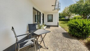 An outdoor patio with a table and chairs, a building with a white exterior, and a hedge. - Apartment 'Bubach' with Private Terrace, Shared Garden and Wi-Fi (Bubach)