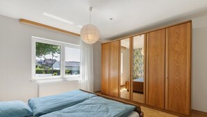 A bedroom with a bed, a wardrobe, a window, and a hanging light fixture. - Apartment 'Bubach' with Private Terrace, Shared Garden and Wi-Fi (Bubach)