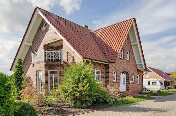 A two-story house with a red-tiled roof, a balcony, and a garden. - Apartment 'Swaalvkenüst' with Balcony and Wi-Fi (Moormerland)
