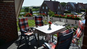 Una terraza con mesa y sillas, vistas a casas y un jardín con flores.