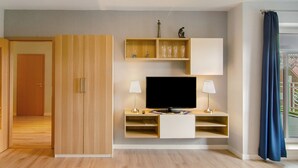 Una habitación moderna con televisión, estanterías y una puerta que da a otra zona.
