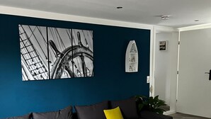 Un salon moderne avec un canapé d’angle, une table basse blanche et un grand tableau abstrait accroché au mur.