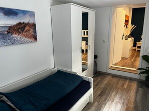 Ein Schlafzimmer mit Bett, Kleiderschrank und Blick auf einen Raum mit Pflanze.