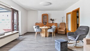 Un salon moderne avec un coin repas, un grand miroir et une vue sur l’extérieur.
