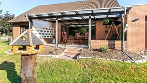 Une maison dotée d’un patio couvert, d’une façade en briques et d’une porte d’entrée.