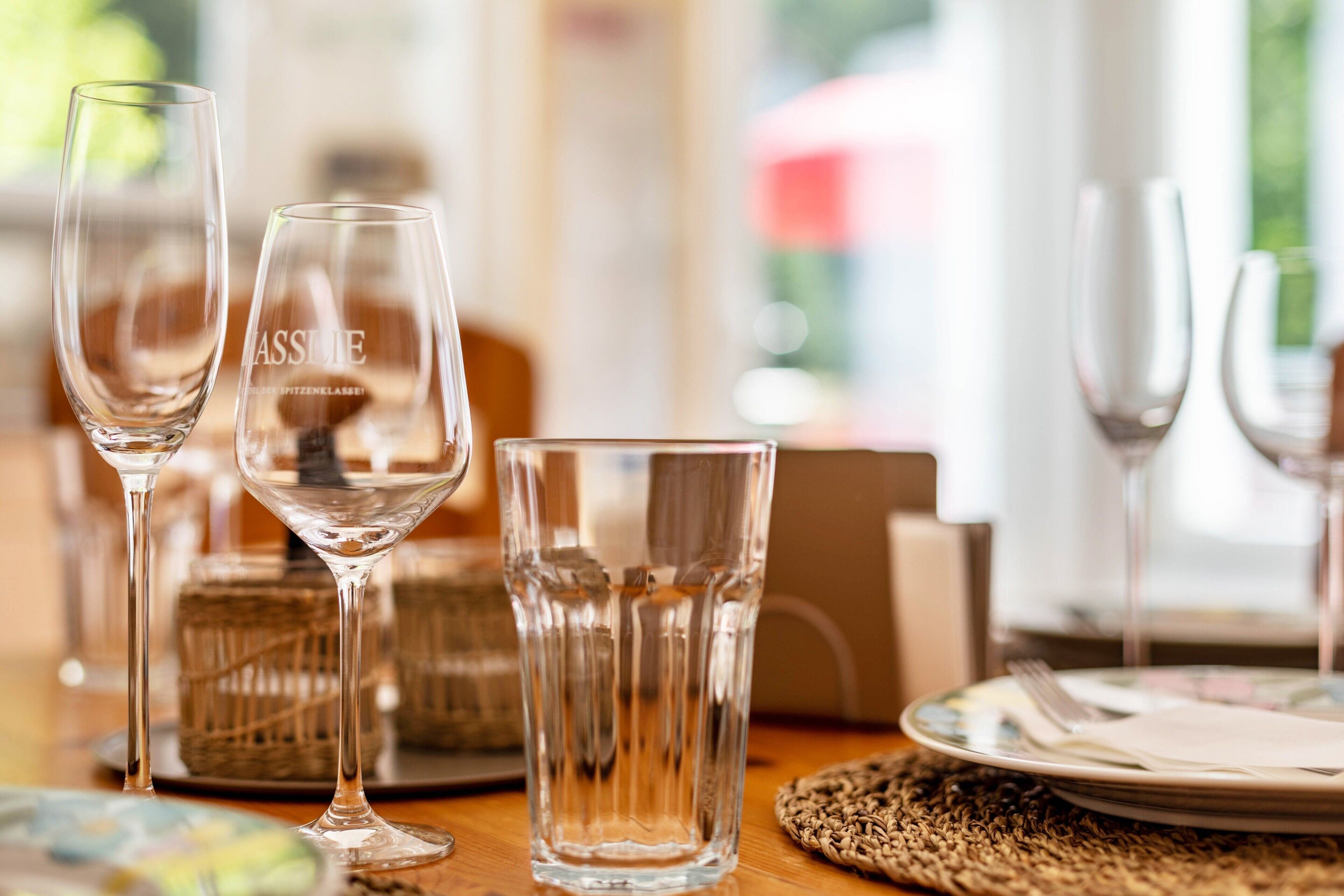 A dining table with clear glassware, a wicker basket, and a plate with a fork and knife.