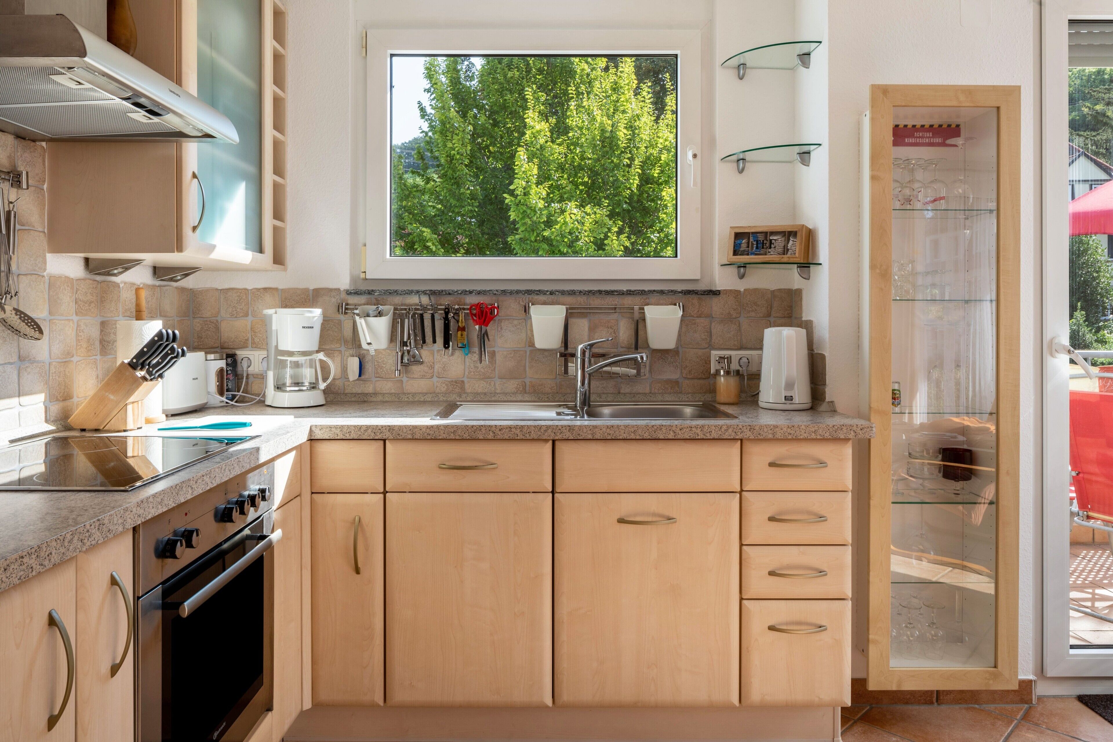 A modern kitchen with a window, stainless steel appliances, and wooden cabinets.