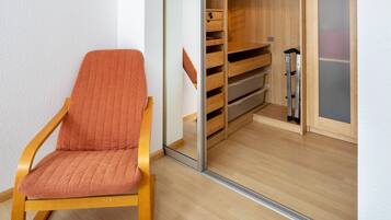 A wooden chair with a cushion, a wooden closet with shelves, and a sliding door.