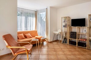 A living room with a sofa, a rocking chair, a TV, and a bookshelf.