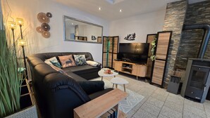 Una sala moderna con un sofá modular, un televisor de pantalla plana, una chimenea y una estantería.