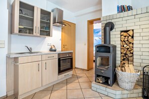 Una cocina con gabinetes de madera, horno empotrado, estufa y chimenea de ladrillo.