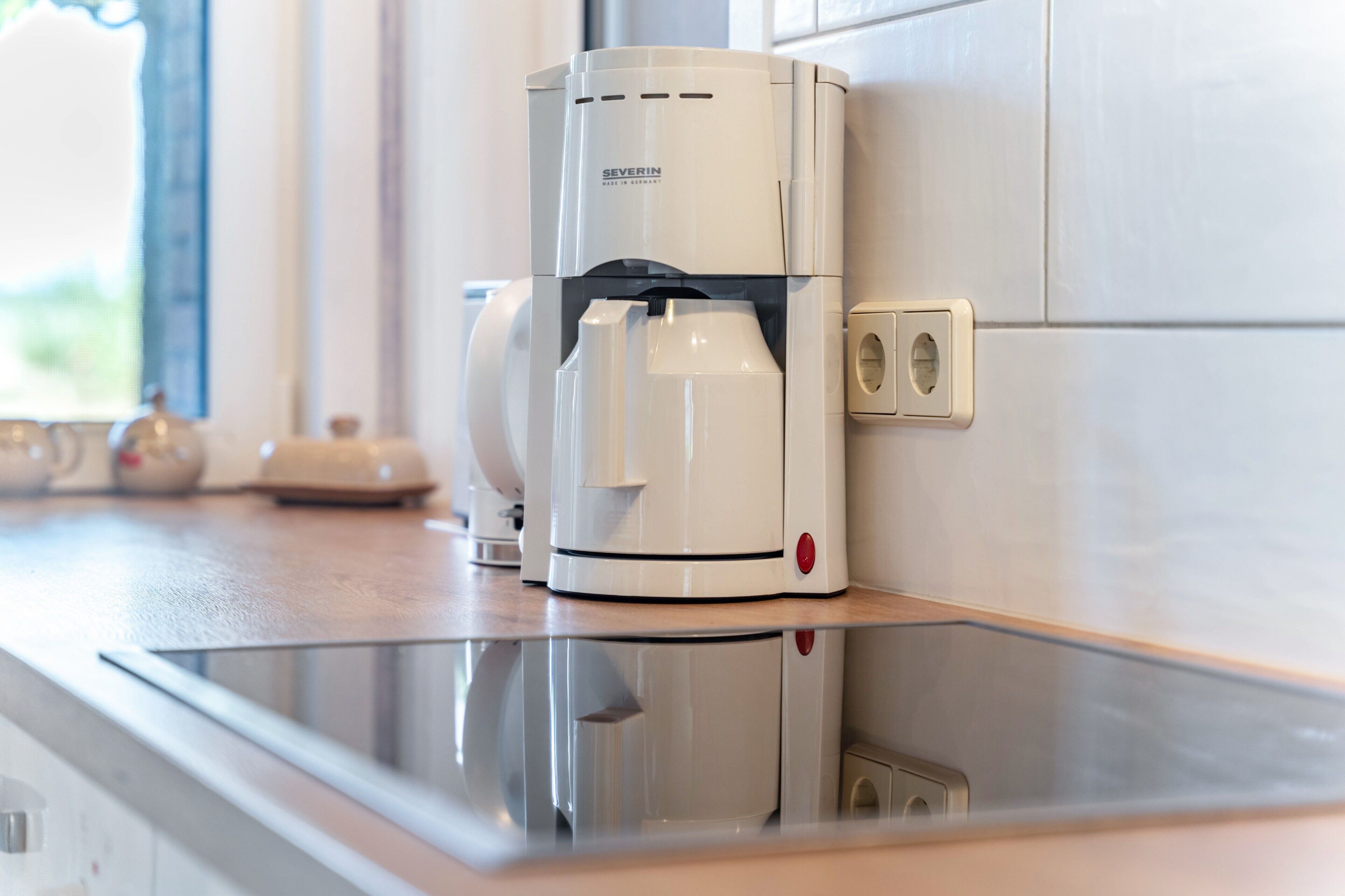 Una macchina da caffè su un piano di lavoro con una presa elettrica a muro.