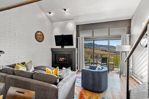 A modern living room with a fireplace, a television, and a balcony with a scenic view.