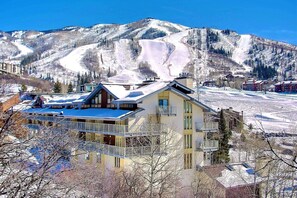 A hotel with a balcony, a mountain view, and a ski slope in the background.