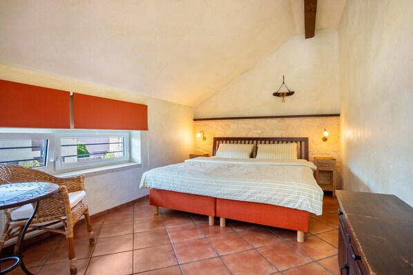 Un dormitorio con una cama, una ventana, una silla y una mesita de noche.