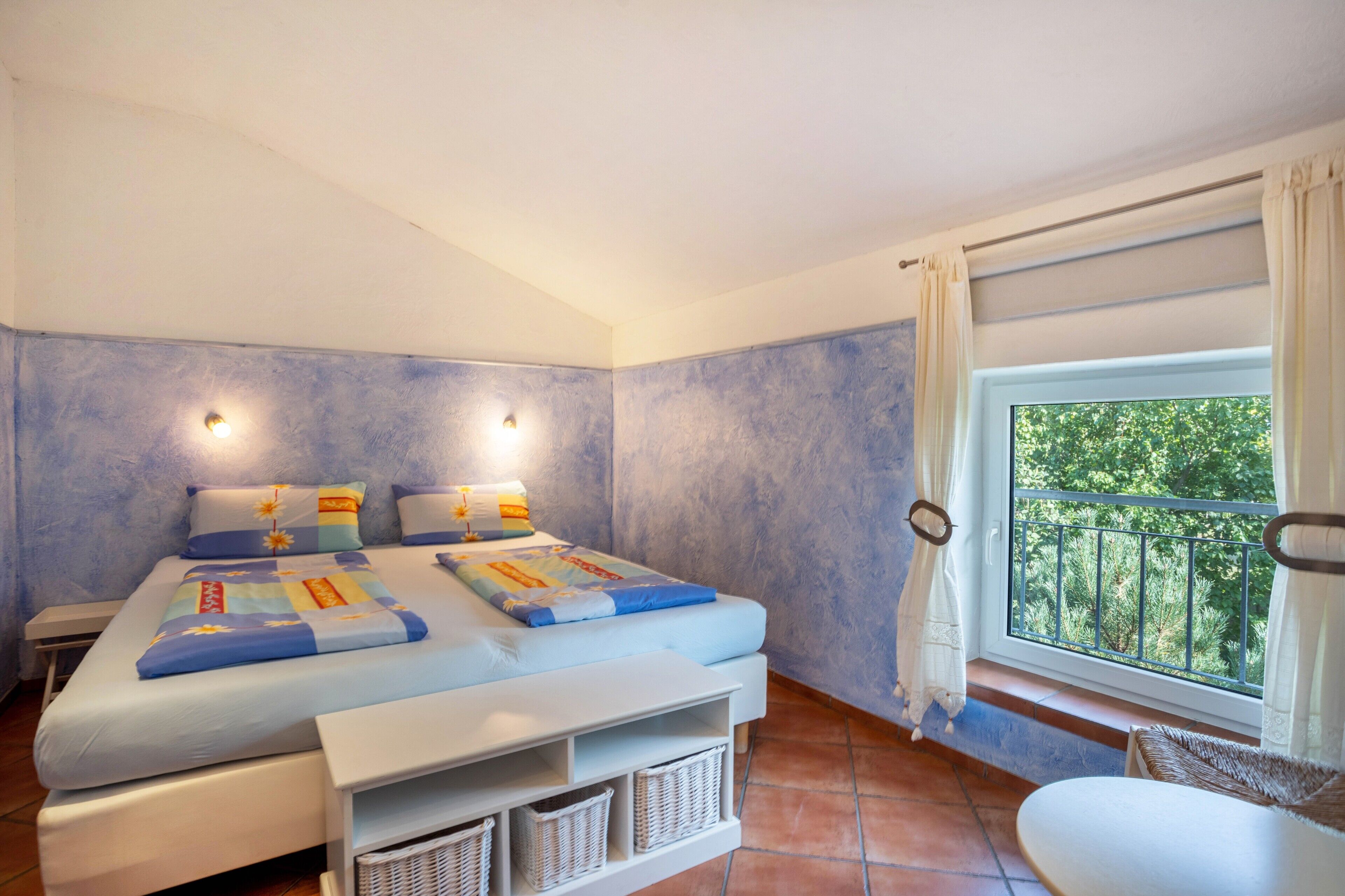 Een slaapkamer met een bed, nachtkastjes, een raam met uitzicht en een balkon.