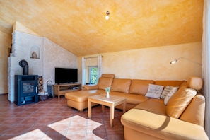 Una sala de estar con chimenea de piedra, televisor, sofá y una mesa de centro.