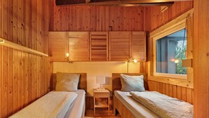 Una habitación de cabaña de madera con dos camas, una mesita y un ventanal.
