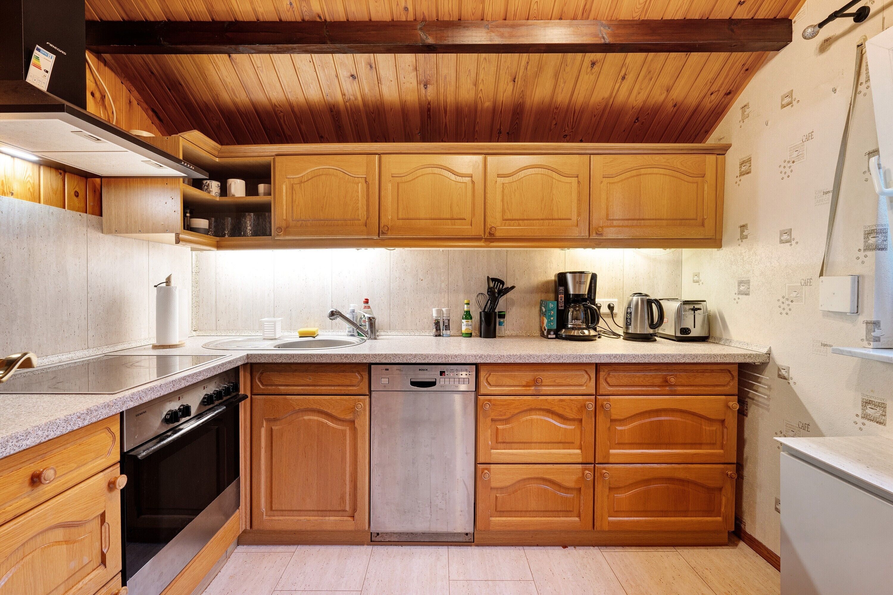 A kitchen with wooden cabinets, a dishwasher, and a coffee maker.