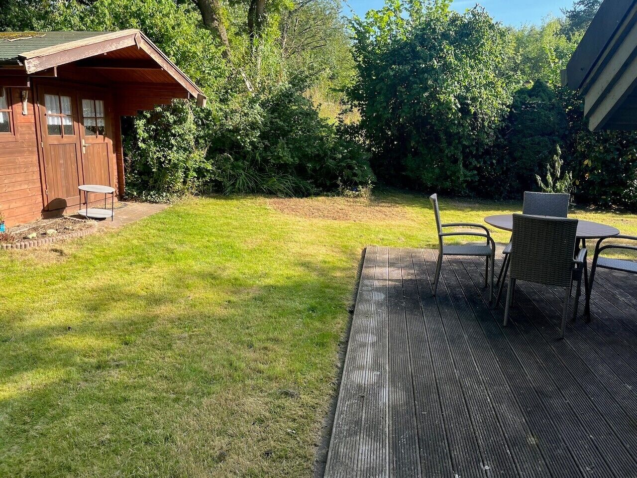A wooden deck with outdoor furniture, a small shed, and a grassy yard.