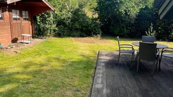 A wooden deck with outdoor furniture, a small shed, and a grassy yard.