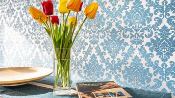 Un jarrón de vidrio transparente con tulipanes sobre una mesa, un libro titulado 'Naturerfahrung mit allen Sinnen' y un plato de madera.
