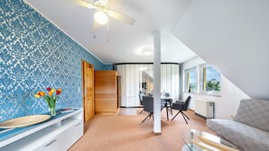 Una habitación moderna con puerta de madera, una zona de comedor con sillas, una mesa de cristal y un sofá.