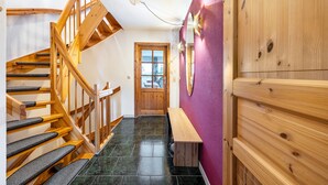 Una escalera de madera con escalones acolchados negros, un banco de madera y una puerta con un ventanal esmerilado.