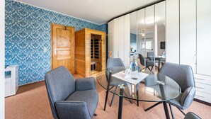 Una habitación moderna con pared de azul y blanco estampada, un mueble de madera, una mesa de vidrio y sillas grises.