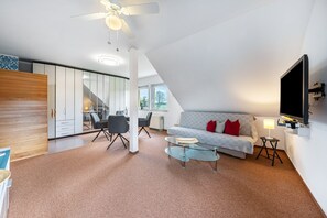 A modern living room with a sofa, coffee table, and a ceiling fan. - Apartment 'Fewo Energiepunkt Am Planitzwald' with Private Terrace, Private Garden and Wi-Fi (Bennewitz)