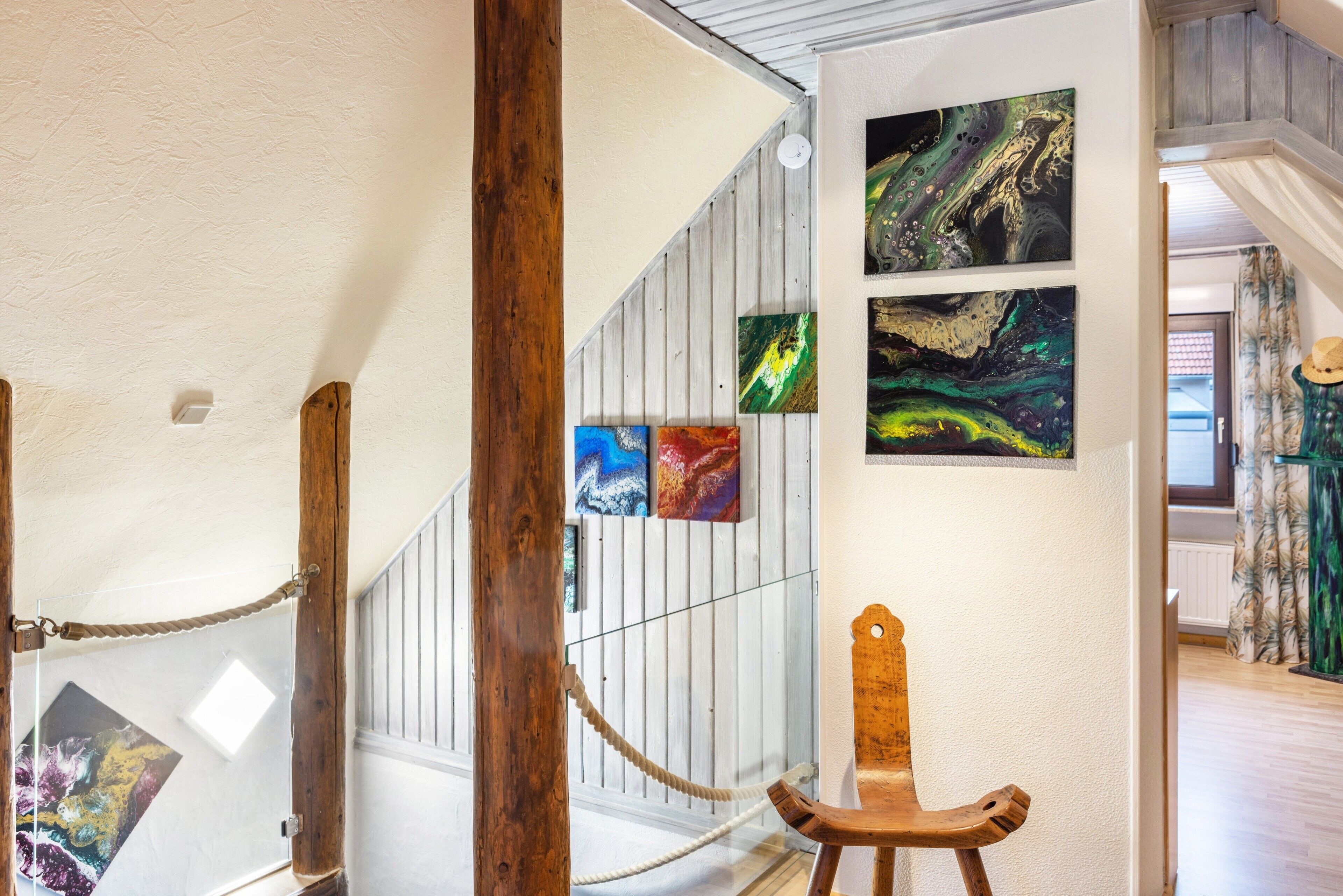 Eine Treppe mit Holzwändungen, einem Seilabfangnetz und einem Holzstuhl.