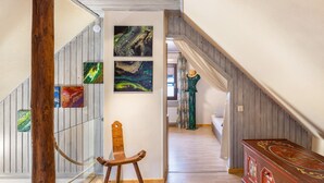 Una escalera con barandillas de madera, una silla de madera y un aparador decorativo.