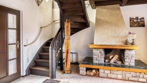 Una escalera con barandilla de madera, una chimenea de piedra con repisa y una puerta con paneles de vidrio esmerilado.