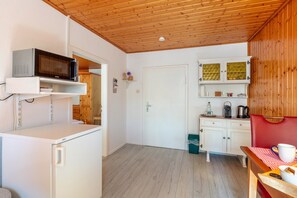 Une cuisine de taille réduite, équipée d’un four à micro-ondes, de meubles blancs et d’un plafond en bois.