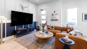 Una sala de estar moderna con un televisor de pantalla plana, un sofá, una mesa de centro y una estantería.
