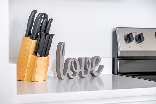 A kitchen counter with a knife block and a 'love' sign.