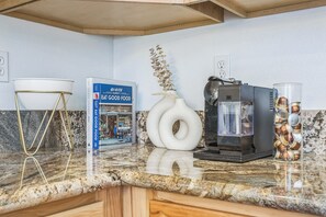 A kitchen counter with a coffee maker, a book titled "Eat Good Food," and a decorative vase.