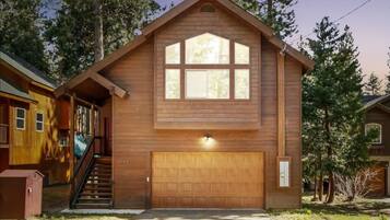 Una casa in legno con un garage, una scala che conduce all'ingresso e un piccolo deposito a sinistra.