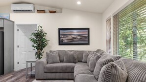 A modern living room with a grey sectional sofa, a potted plant, and a framed picture on the wall.