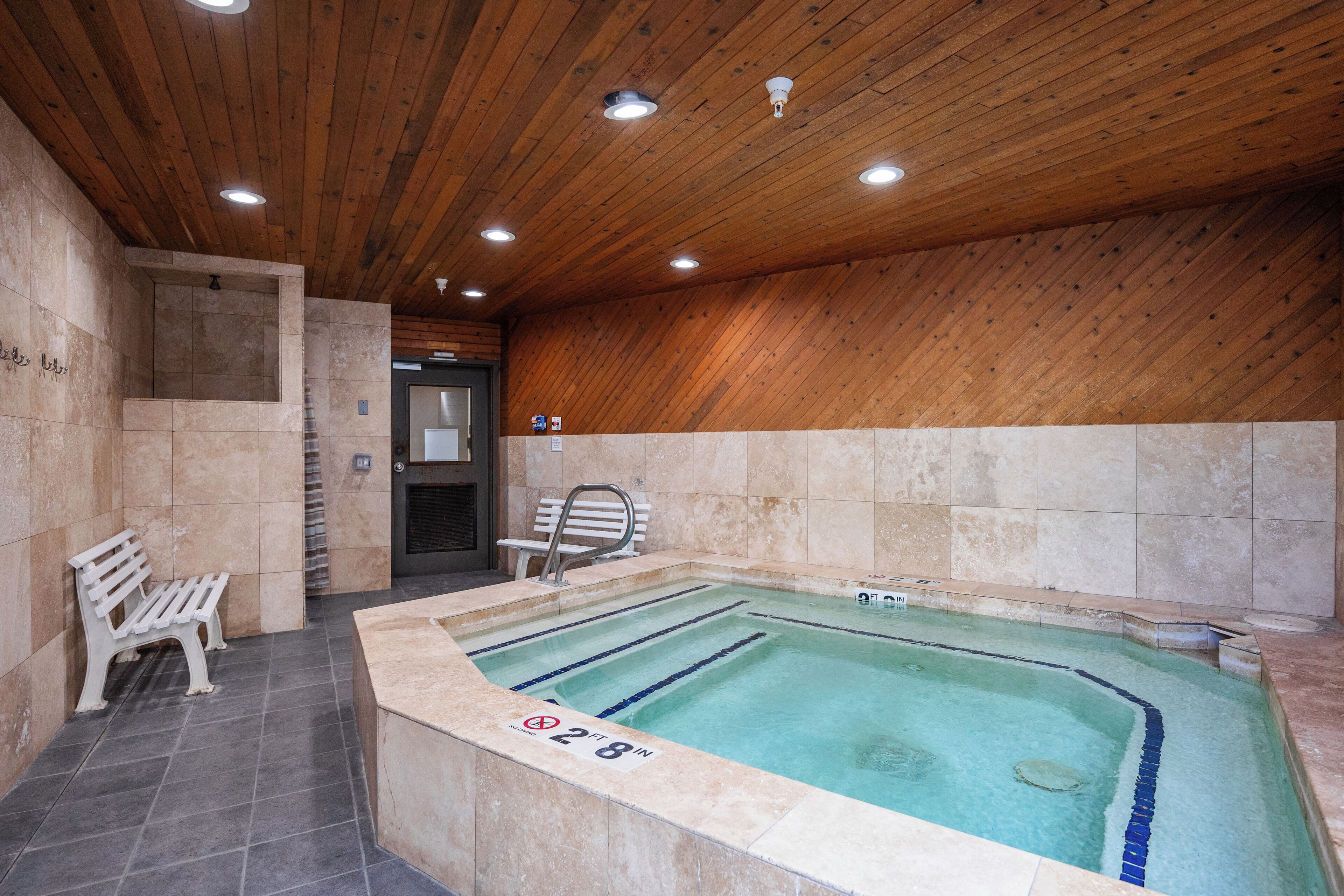 Et spa-område med jacuzzi, træloft og fliserede vægge.