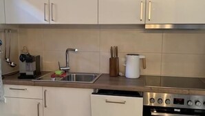 A modern kitchen with white cabinets, a stainless steel oven, and a sink. - Lomasi, 65 sqm, 1 bedroom, ground floor, terrace (Marquartstein)