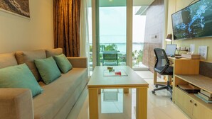 A modern living room with a sofa, a coffee table, a TV, and a balcony with a view of the sea. - Sea View Beach Bar Beach Front c114 (Rawai)